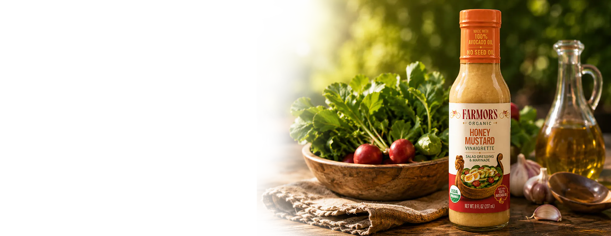 A bottle of Farmor’s Honey Mustard Vinaigrette beside a bowl of radishes, fresh greens and a jug of olive oil