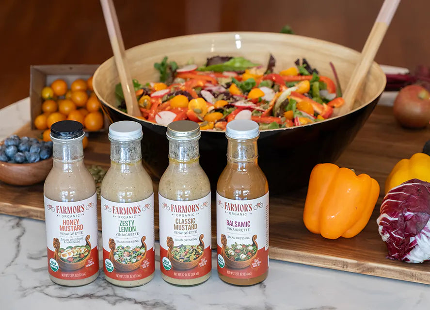 Four Farmor’s bottles in front of a salad bowl and fresh produce