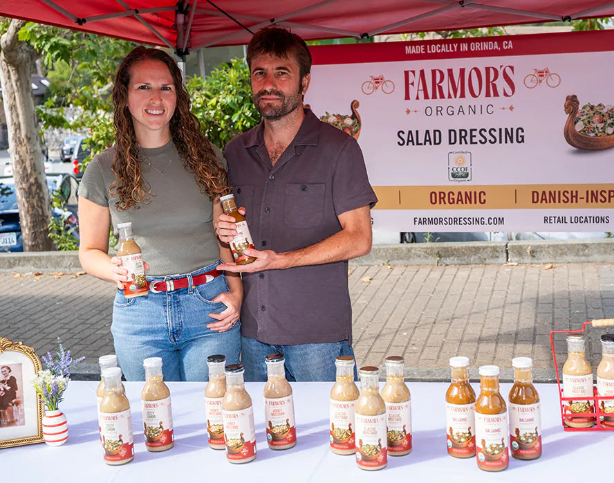 Alex and Adam at the Farmor’s farmers market booth in Orinda, holding two bottles
